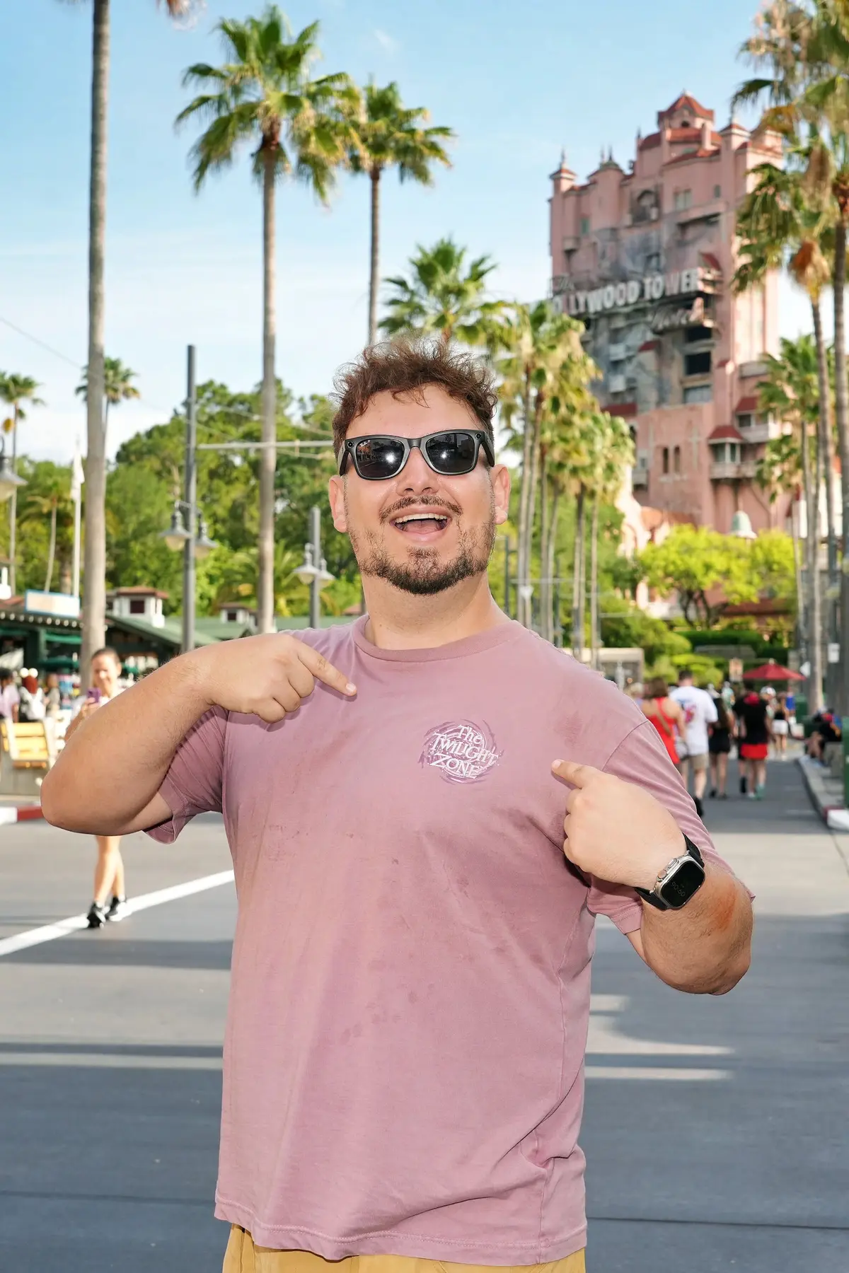 Thomaz, guia da Desenrola, aponta para si mesmo na Sunset Boulevard, com a Tower of Terror ao fundo
