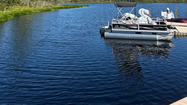Lago de águas calmas com pontão e pedalinhos de cisne atracados sob céu azul, na Flórida