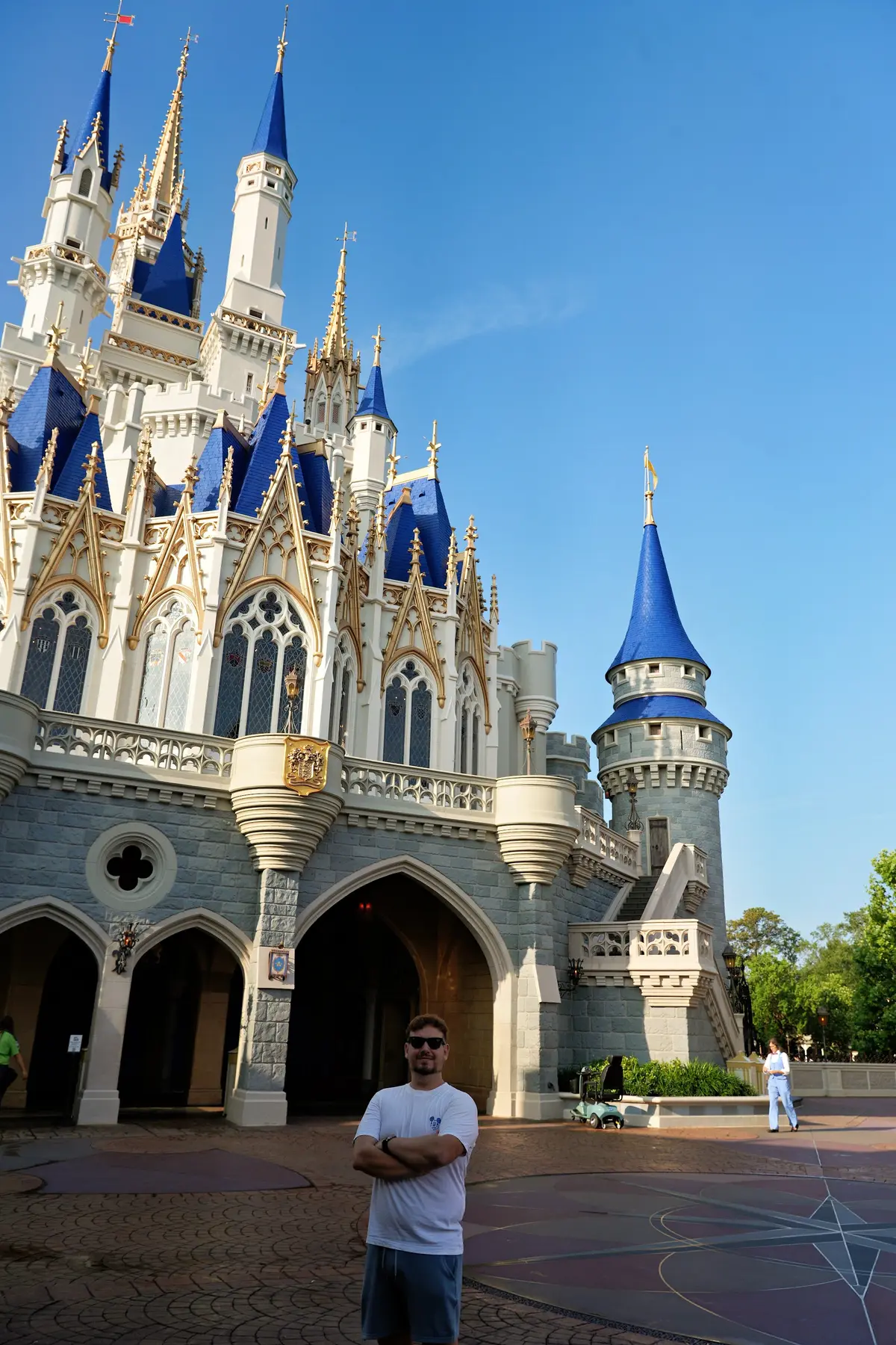 Thomaz de braços cruzados diante do Castelo da Cinderela, com o parque ainda vazio, no Magic Kingdom