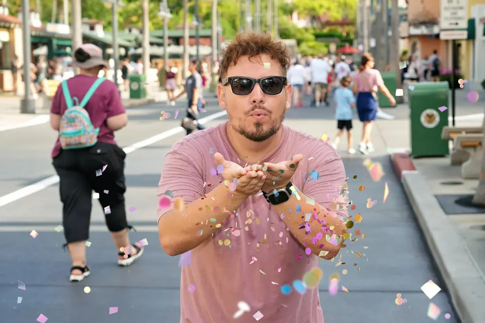 Thomaz soprando confete colorido em direção à câmera na Hollywood Blvd