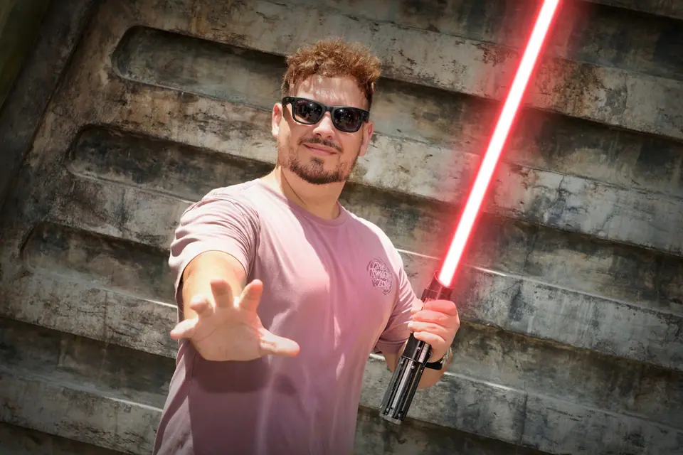 Thomaz com sabre de luz vermelho fazendo gesto da Força em parede de Star Wars