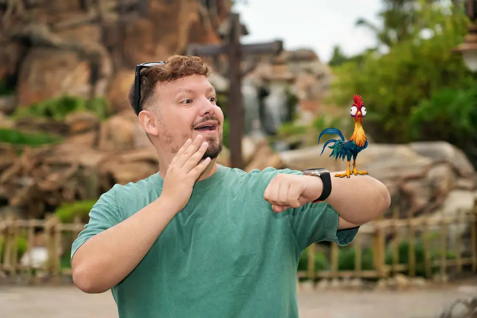 Thomaz fazendo cara de surpresa e falando, com o galo Heihei (Moana, efeito Magic Shot) no braço, na Árvore da Vida, dia