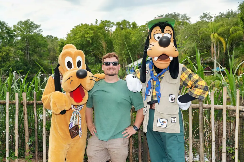 Thomaz com Pluto e Pateta em trajes safári no encontro com personagens ao ar livre, dia