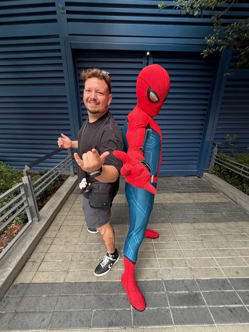 Thomaz fazendo pose divertida (hang loose) ao lado do Homem-Aranha no Avengers Campus