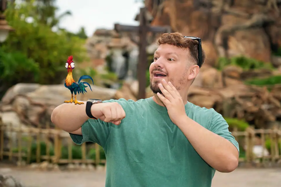 Thomaz, da Desenrola Turismo, se divertindo com o galo Heihei, de Moana, no Animal Kingdom
