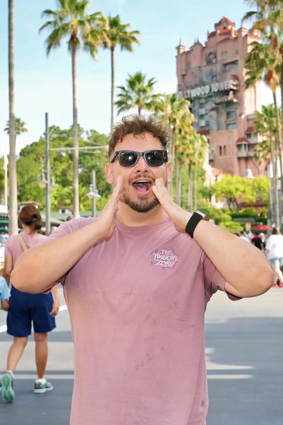 Thomaz, guia da Desenrola, chamando o grupo no Hollywood Studios com a Tower of Terror ao fundo
